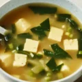 Homemade miso soup in a ceramic bowl featuring silken tofu, seaweed, and scallions in a rich umami dashi broth
