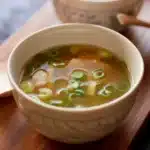 Delicious bowl of homemade miso soup with tofu, green onions, and fresh greens.