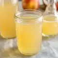 Homemade apple cider vinegar recipe with apples, sugar, and water in a jar.