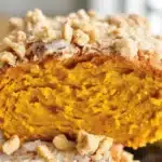 Slice of pumpkin coffee cake with crumb topping, showcasing its moist texture and warm spices.