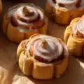 Delicious pumpkin cinnamon rolls with cream cheese icing on a rustic wooden table.