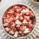 Bowl of Bloody Red Velvet Popcorn drizzled with white chocolate and red syrup.