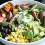 Sweet potato taco bowl topped with zesty meat, black beans, and fresh veggies.