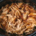 Delicious shredded Crockpot BBQ Chicken served with garnishes.