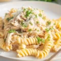 Delicious Crockpot Garlic Parmesan Chicken served with pasta and garnished with herbs.