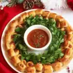 Festive Holiday Pigs in a Blanket Wreath appetizer with mini sausages and crescent dough.