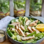 Grilled Chicken Caesar Pasta Salad Jars with layers of romaine, chicken, and pasta.