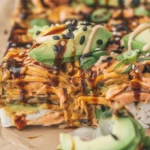 Spicy Salmon Sushi Bake topped with creamy mayo, layered in a casserole dish.