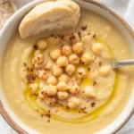 A bowl of creamy Vegan Garlic Chickpea Soup garnished with crispy chickpeas and herbs.