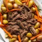 Tender Slow Cooker Pot Roast served with potatoes and carrots in rich gravy.