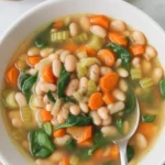 Hearty white bean soup with fresh herbs and vegetables in a cozy bowl.