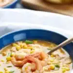 Bowl of creamy Shrimp and Corn Chowder with bacon and corn on a rustic table.