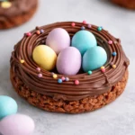 Easter Birds Nest Cookies Recipe with chocolate and candy eggs on a pink background.