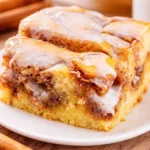 Delicious Cinnamon roll cake topped with vanilla icing and cinnamon swirl.