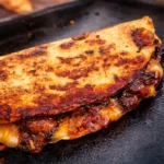Delicious Blackstone Hot Honey BBQ Chicken Quesadillas cooked on a griddle, featuring a spicy and sweet flavor.
