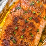 Garlic Butter Baked Salmon on a plate with fresh herbs and lemon slices