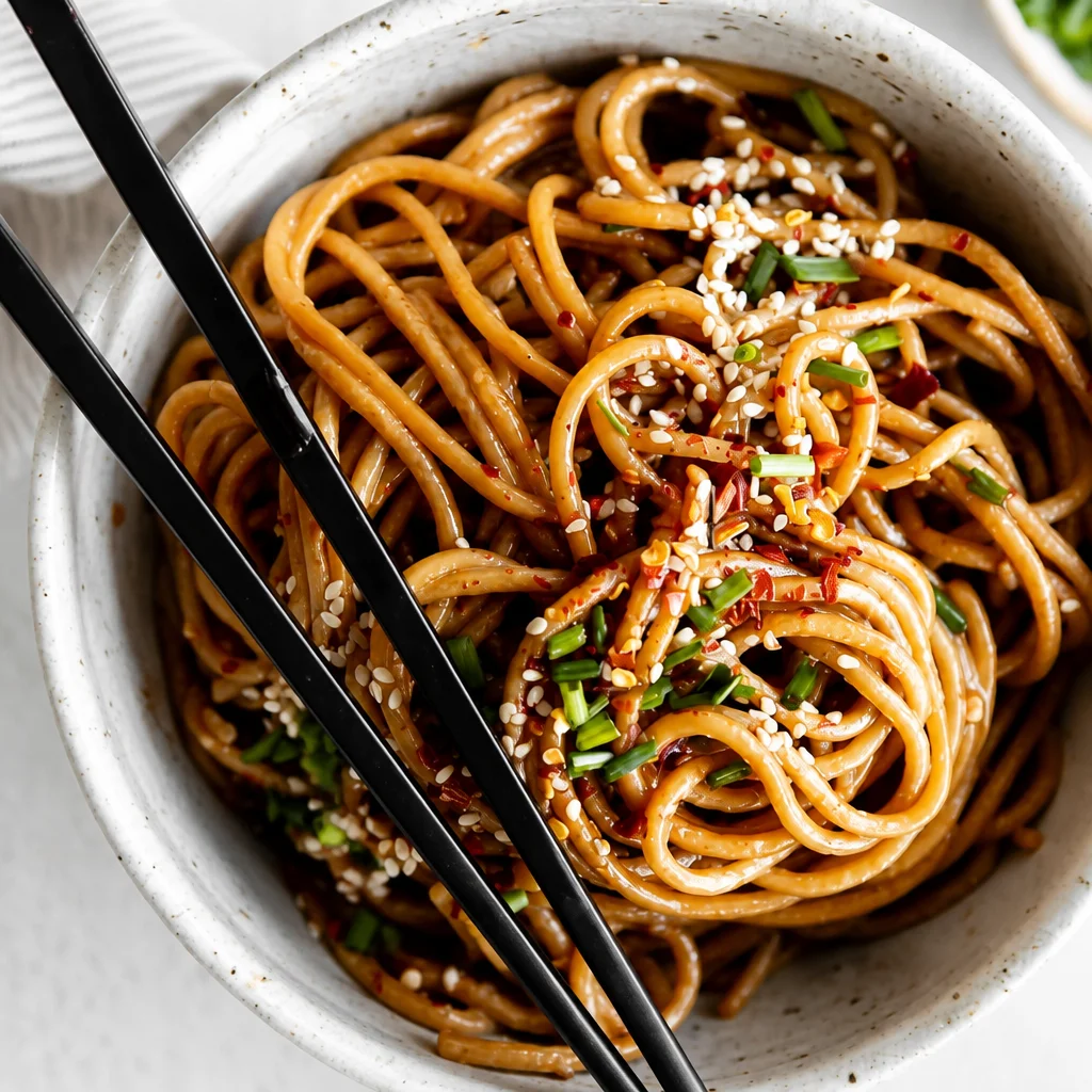Plate of easy Garlic Sesame Noodles garnished with sesame seeds and green onions.