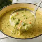 Bowl of rich and creamy high protein broccoli cheddar soup topped with cheese.
