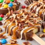 Vegan caramel apple slices drizzled with chocolate and topped with nuts.